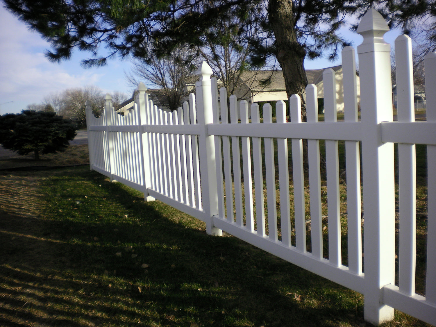 White picket fence with trees and a house in Redwood, California.