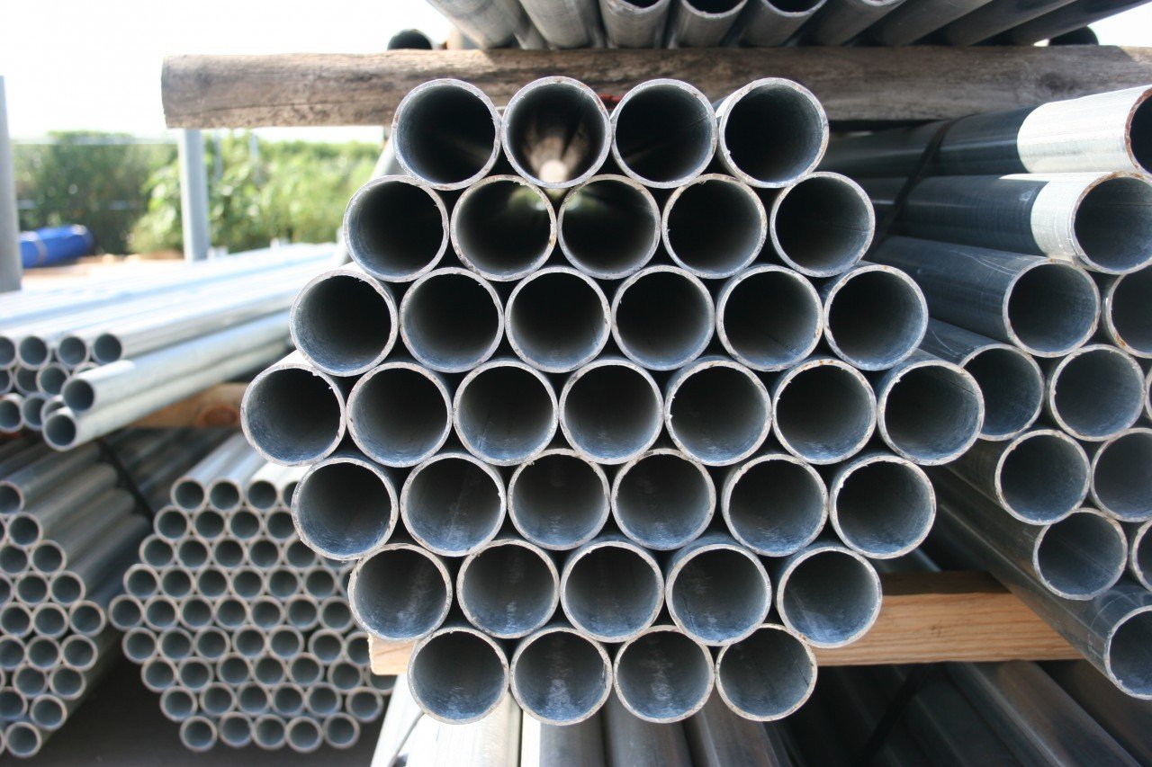 Stacks of metal pipes in a fence company's yard.