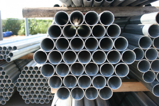 Stacks of metal pipes in a fence company's yard.