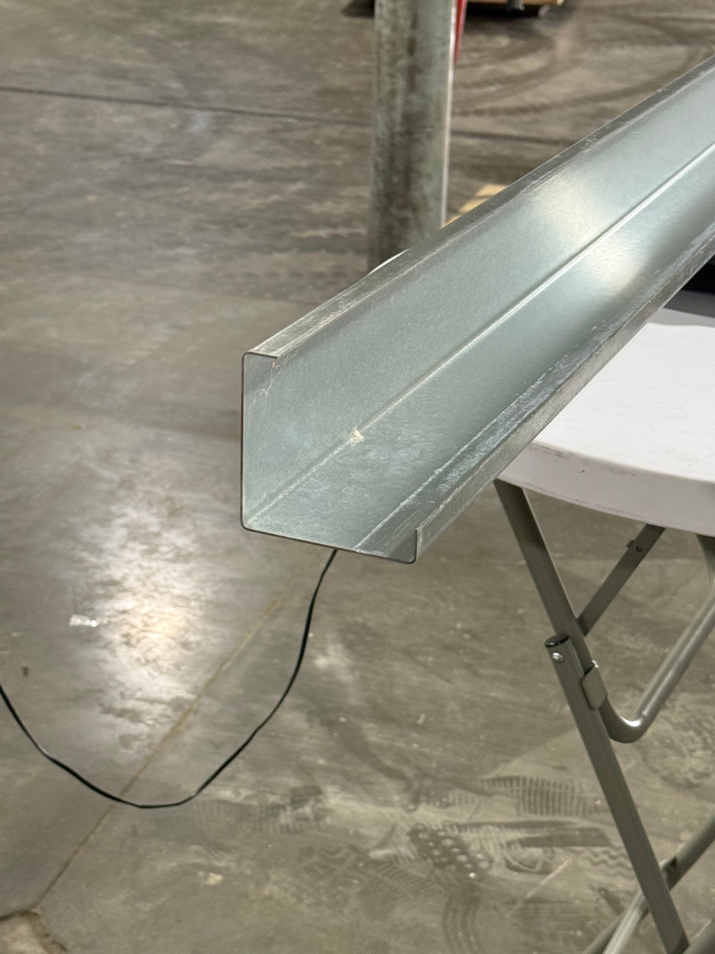 A metal post insert for vinyl fences in a shop setting.
