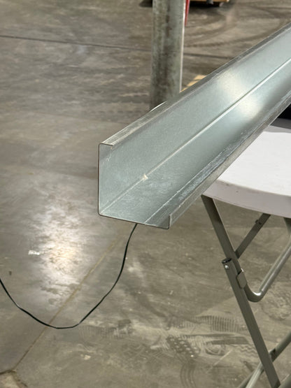 A metal post insert for vinyl fences in a shop setting.